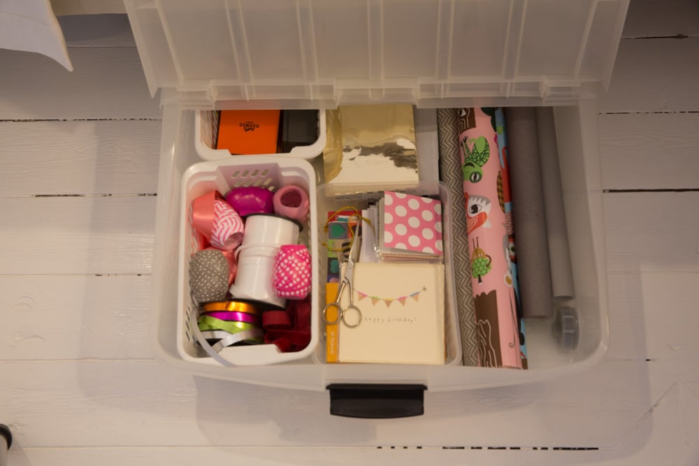 Plastlåda med olika presentinslagningstillbehör som färgglada band, kort och presentpapper